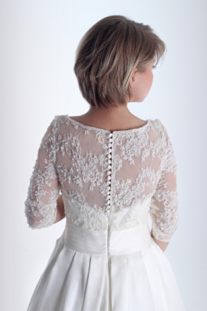Espalda del vestido de novia en alquiler Cándida de Innovias con talle bordado de encaje y manga francesa